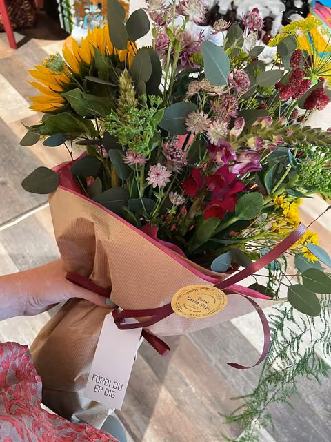 Farverig buket bliver pakket ind med papir og bånd i butikken